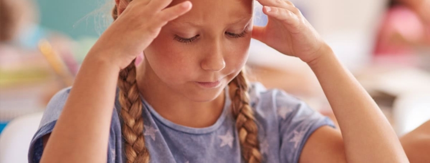 Dolore testa bambini scuola, mal di testa ragazza studio, salute e cura bambini, gestione stress scolastico, supporto medico pediatrico per mal di testa.