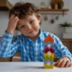 Giovane bambino che gioca con torri di blocchi colorati in cucina, immagini di gioco e creatività infantile, ambiente domestico accogliente e sicuro, stimolazione mentale e sviluppo delle capacità motorie.