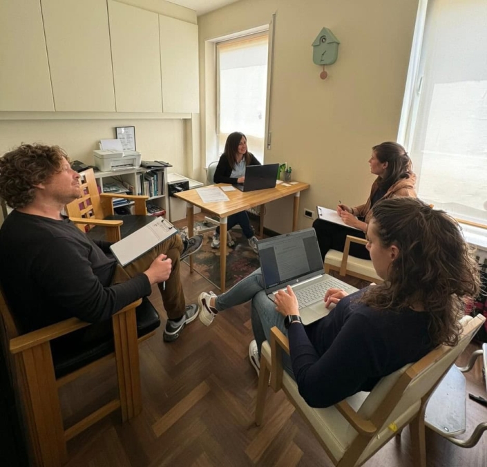 Professionisti in riunione in ufficio con computer portatili e documenti, ambiente lavorativo professionale, collaborazione e brainstorming, stile moderno e accogliente, immagini di lavoro e team.