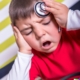 Ragazzo traumatizzato con dolore alla testa durante visita medica pediatrica, con medico che esamina la testa del bambino, ambiente clinico, pronto intervento, cura e assistenza pediatric.